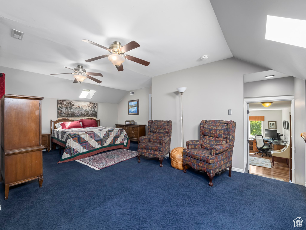 Carpeted bedroom with lofted ceiling with skylight and ceiling fan