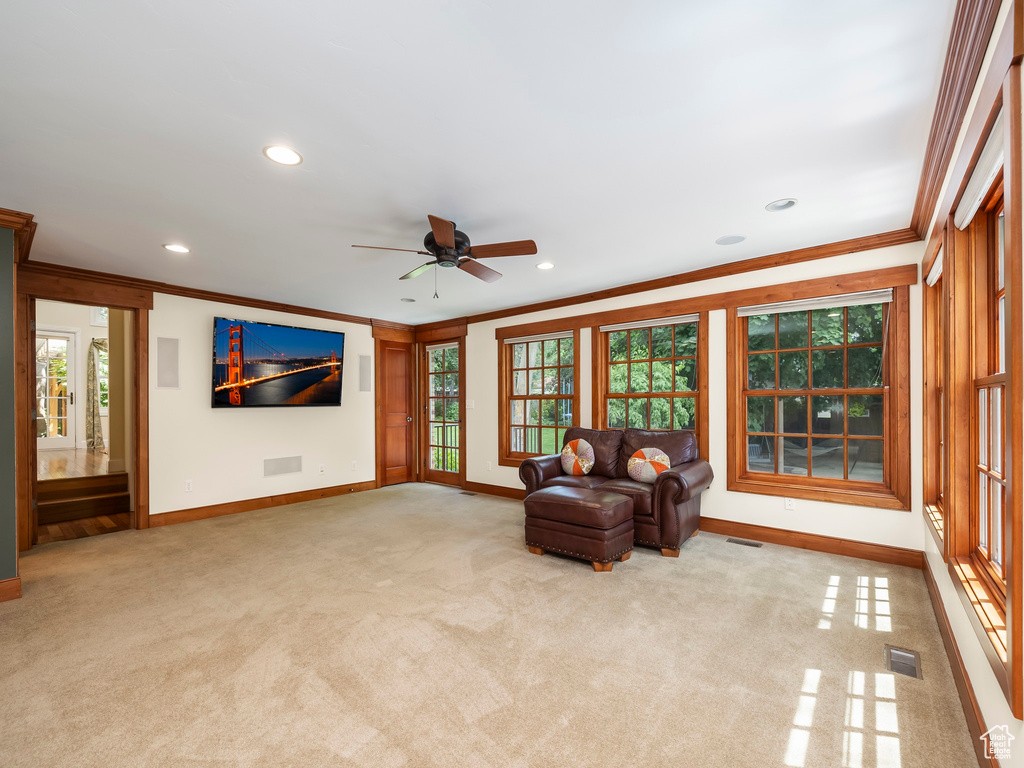 Unfurnished living room featuring ceiling fan, carpet floors, and crown molding