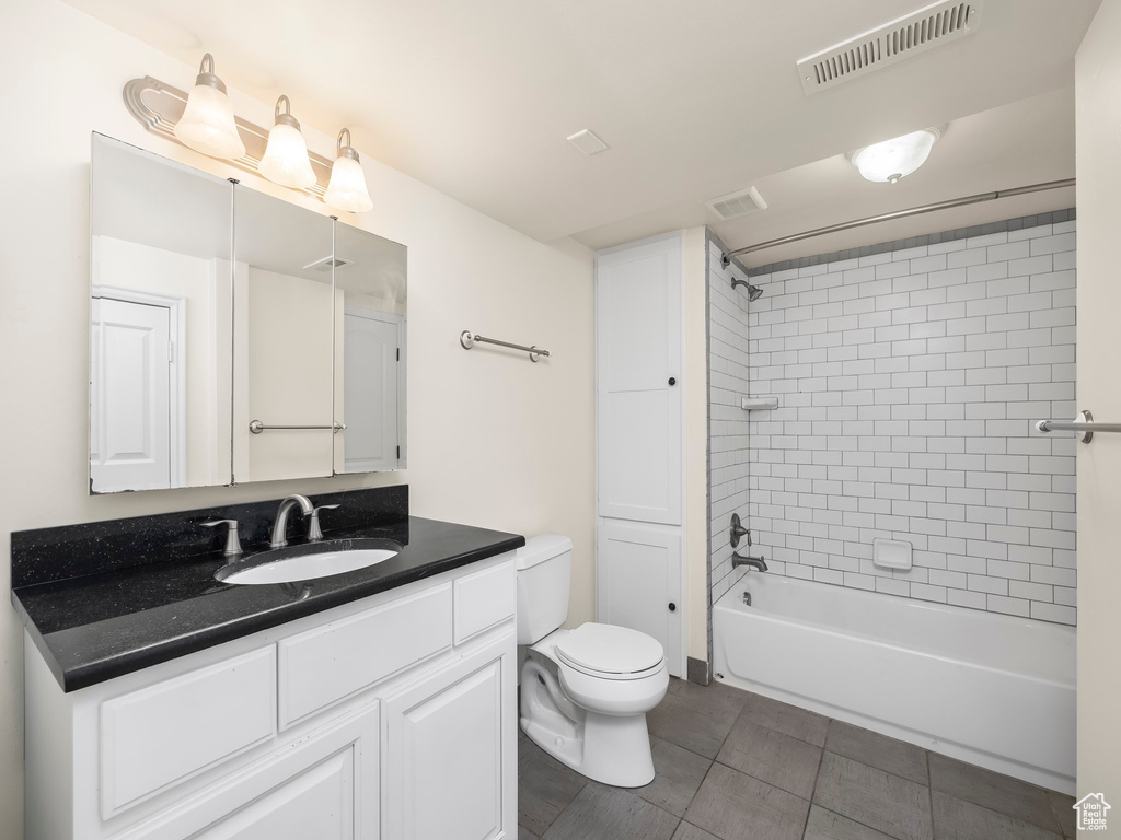 Full bathroom with tile flooring, tiled shower / bath combo, vanity, and toilet