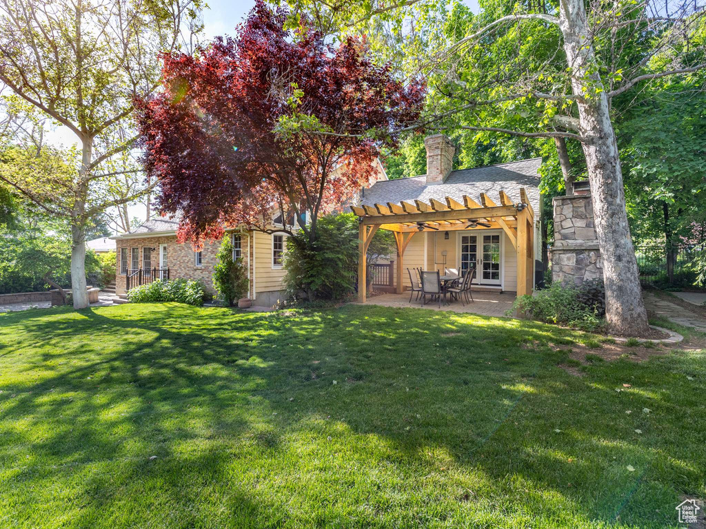 View of front of home with a front yard, a pergola, ceiling fan, and a patio