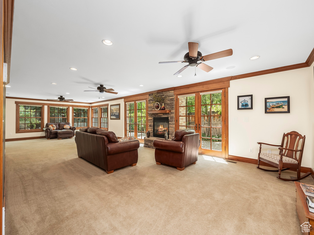 Living room with light carpet, ceiling fan, a fireplace, and crown molding