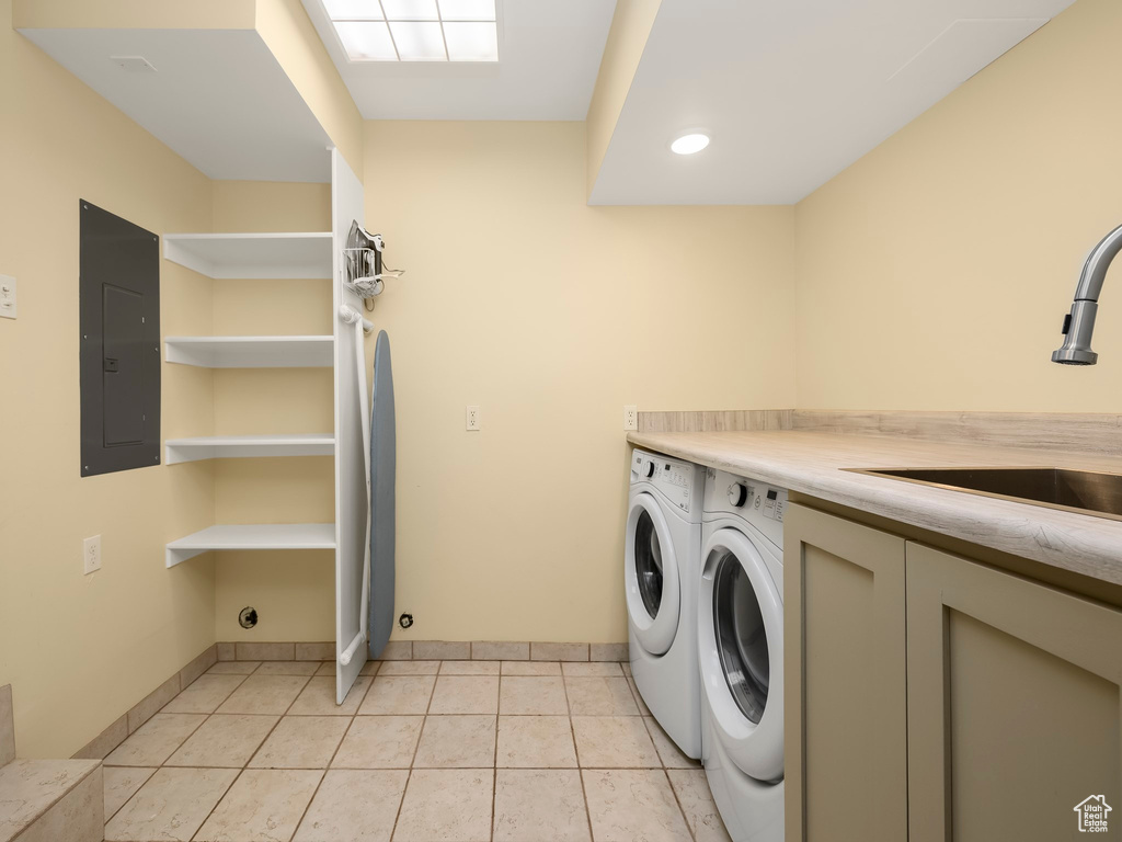 Washroom with sink, light tile flooring, and washing machine and clothes dryer