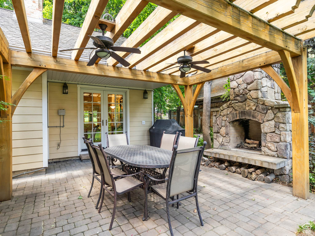 View of patio with an outdoor stone fireplace, area for grilling, ceiling fan, and a pergola