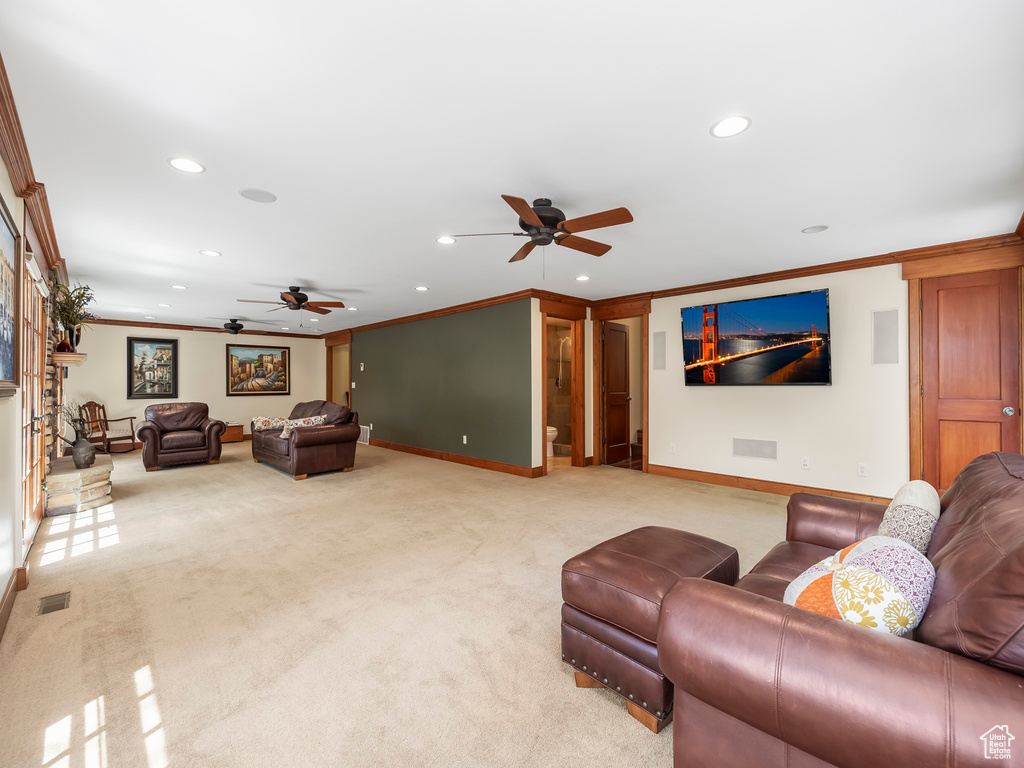 Living room with ceiling fan, carpet floors, and crown molding