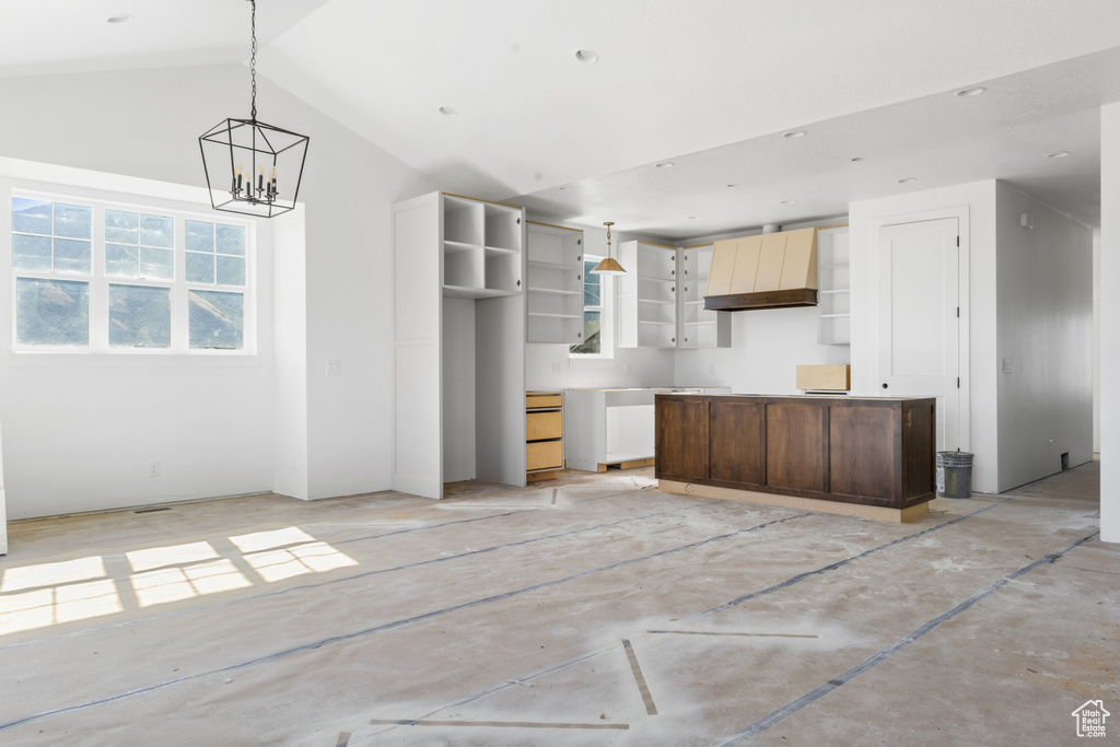 Kitchen with custom exhaust hood, a chandelier, hanging light fixtures, high vaulted ceiling, and a kitchen island