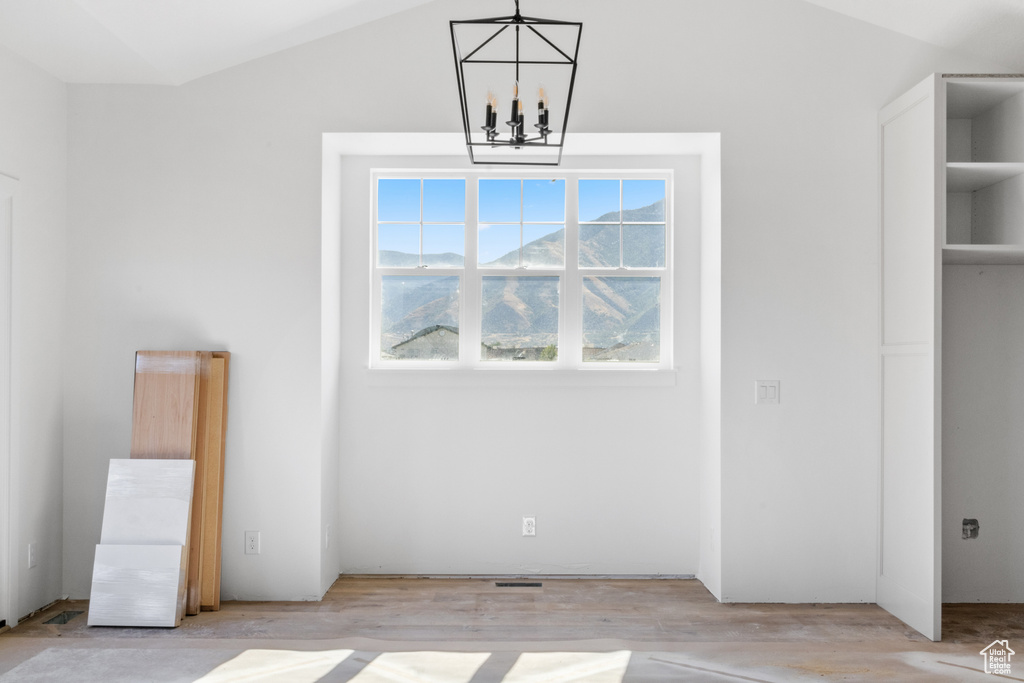 Interior space featuring an inviting chandelier, light wood-type flooring, and lofted ceiling