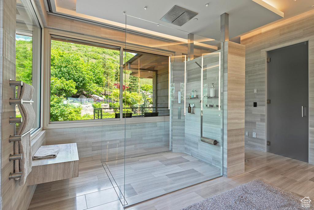 Bathroom featuring tile walls, tile floors, and a shower with door