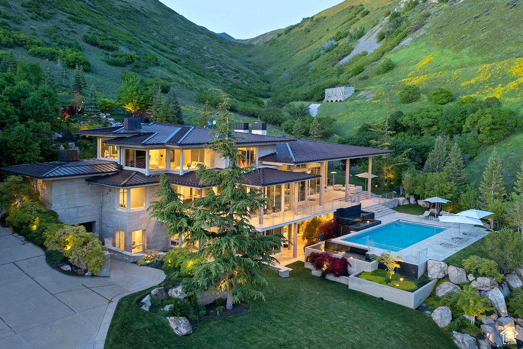 Back of property featuring a patio, a mountain view, and a yard