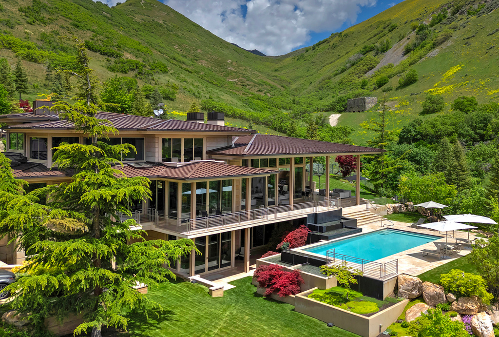 Back of property with a patio area, a balcony, a lawn, and a mountain view