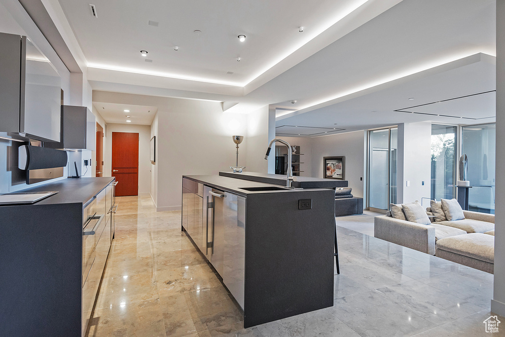 Kitchen featuring an island with sink, sink, light tile flooring, and a breakfast bar