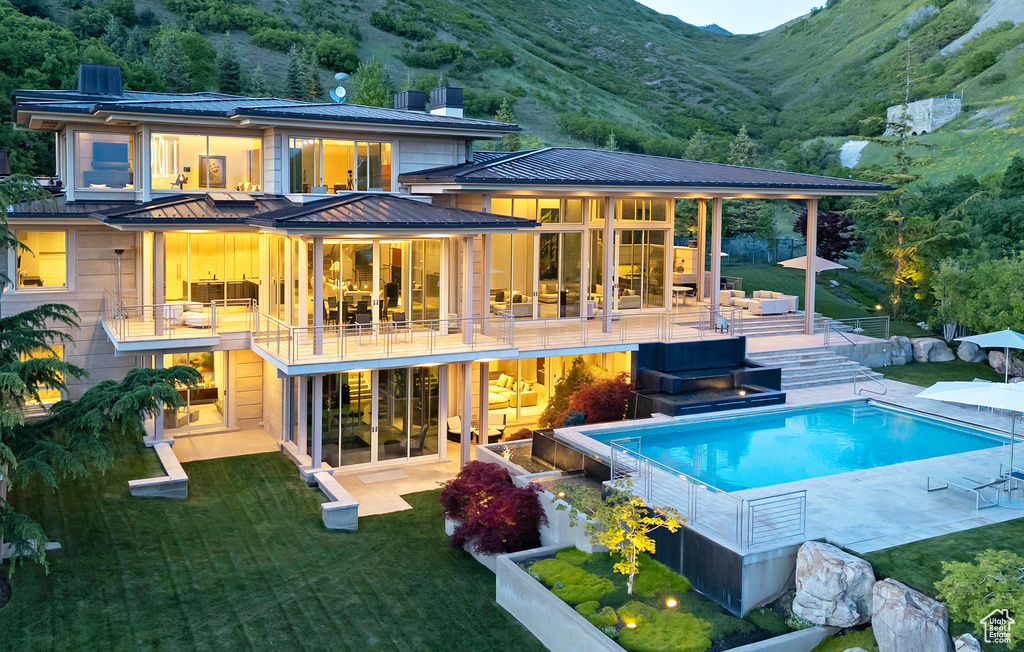 Back of house featuring a patio area, a balcony, a mountain view, and a yard