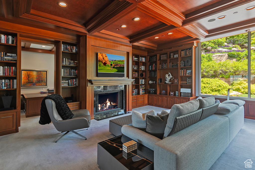 Living room with coffered ceiling, built in shelves, crown molding, and light colored carpet