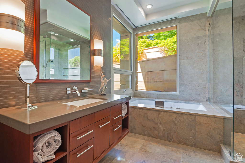 Bathroom featuring tile floors, shower with separate bathtub, tasteful backsplash, and vanity