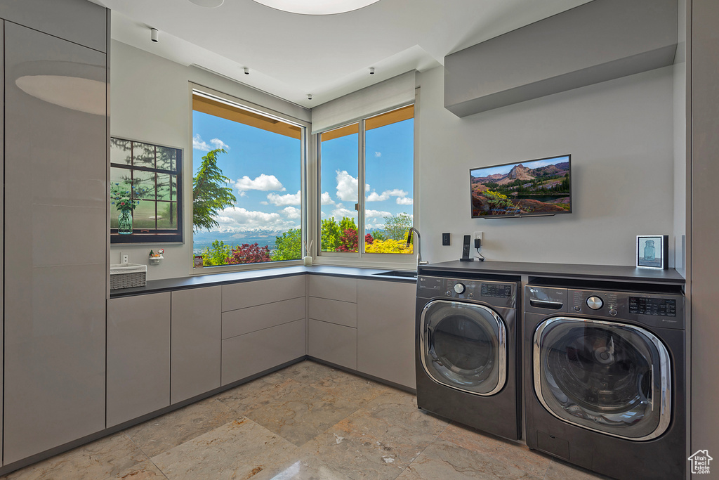 Laundry room featuring sink, light tile flooring, and washing machine and clothes dryer