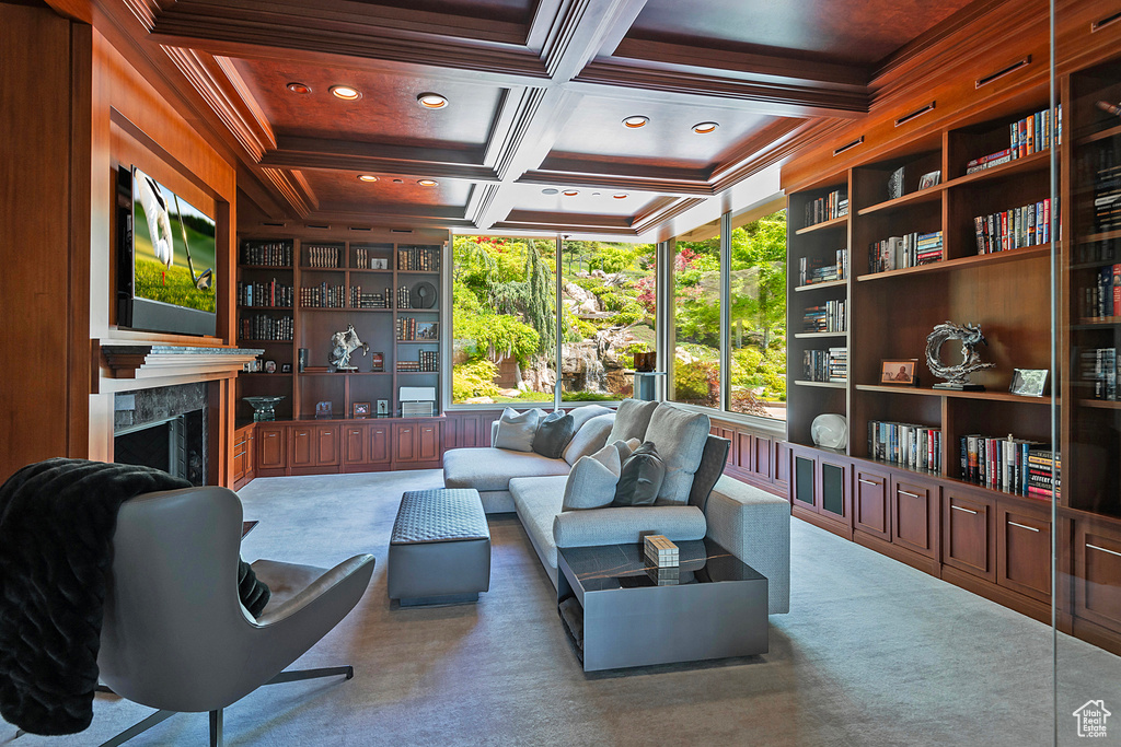 Living room featuring crown molding, a high end fireplace, built in shelves, coffered ceiling, and carpet