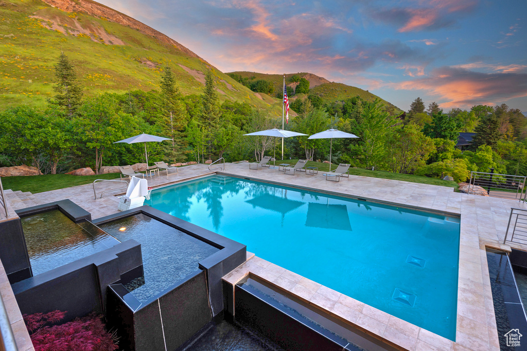 Pool at dusk featuring a patio and a mountain view