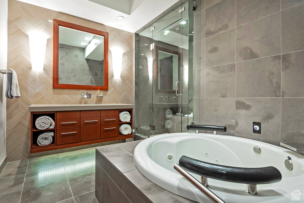 Bathroom with tile floors, tile walls, vanity, and plus walk in shower