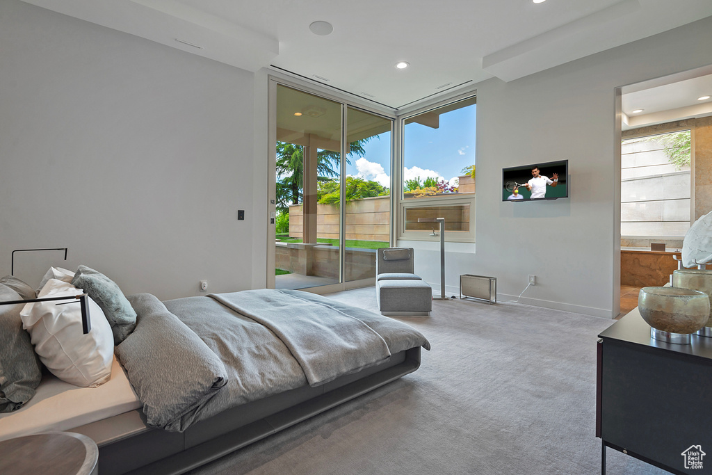 Carpeted bedroom featuring a wall of windows and multiple windows