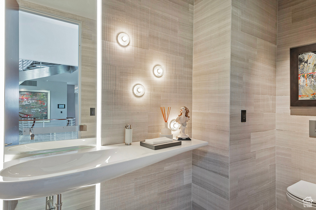 Bathroom with toilet and tile walls