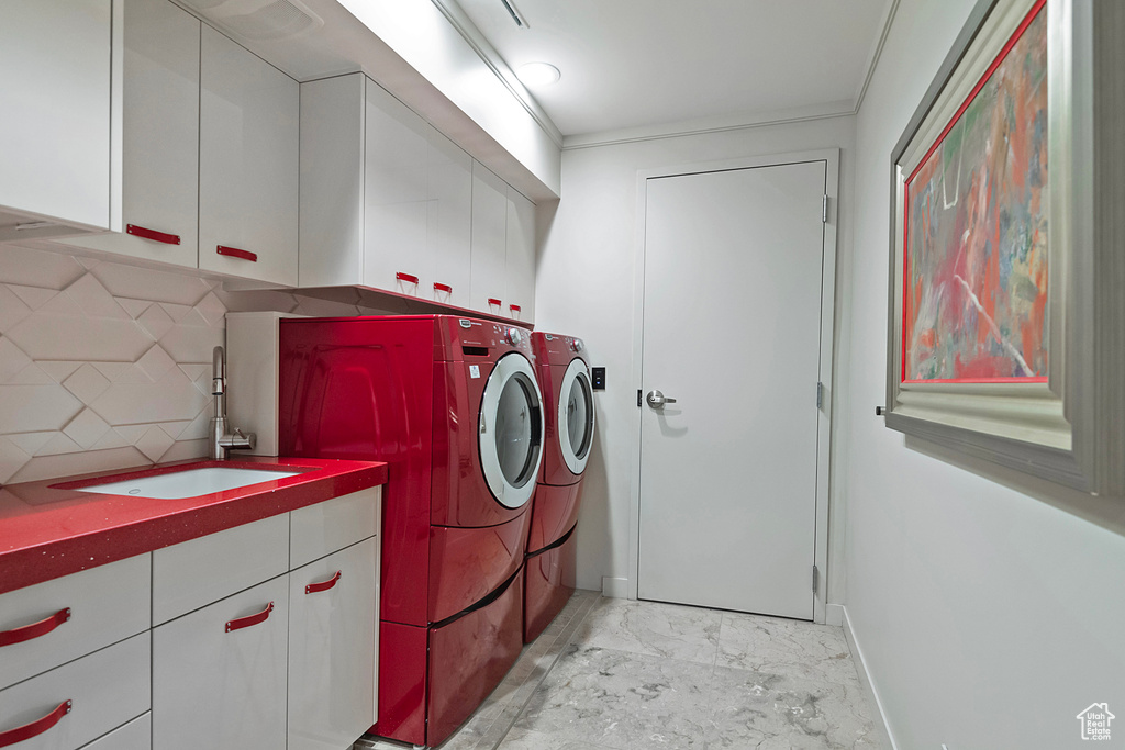 Laundry room featuring sink, washing machine and clothes dryer, cabinets, and light tile floors