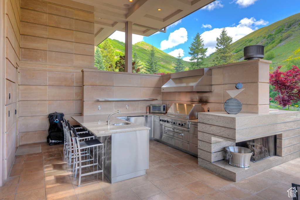 View of patio featuring sink, a mountain view, a grill, and an outdoor kitchen