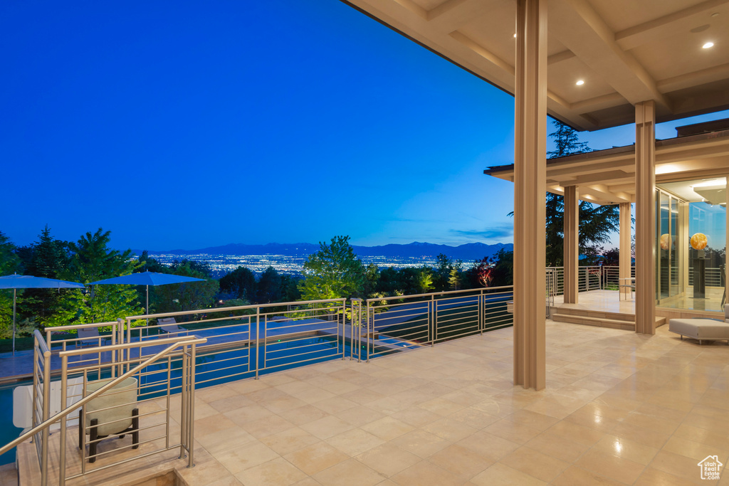 Patio terrace at dusk featuring a balcony and a mountain view