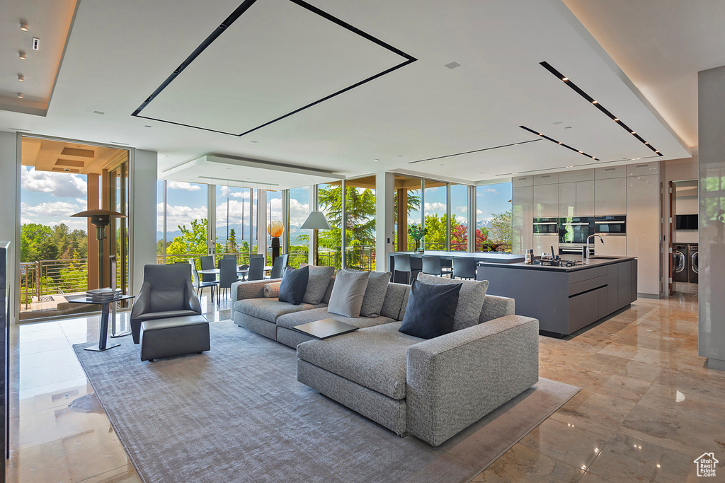 Tiled living room featuring sink, floor to ceiling windows, a wealth of natural light, and independent washer and dryer