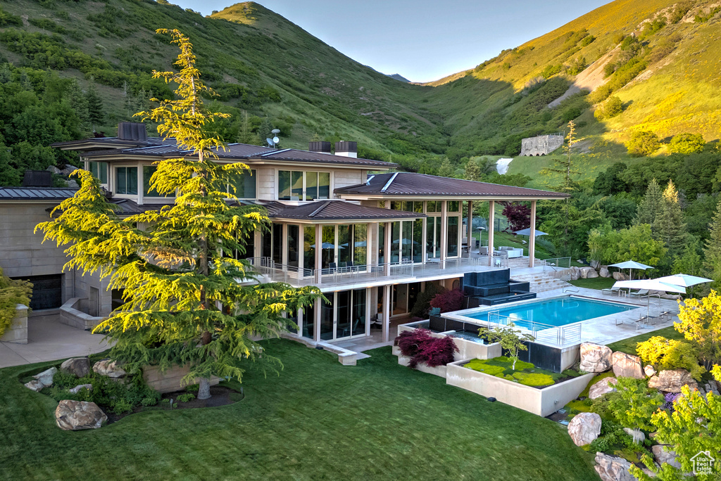 Rear view of property with a patio, a balcony, a lawn, and a mountain view