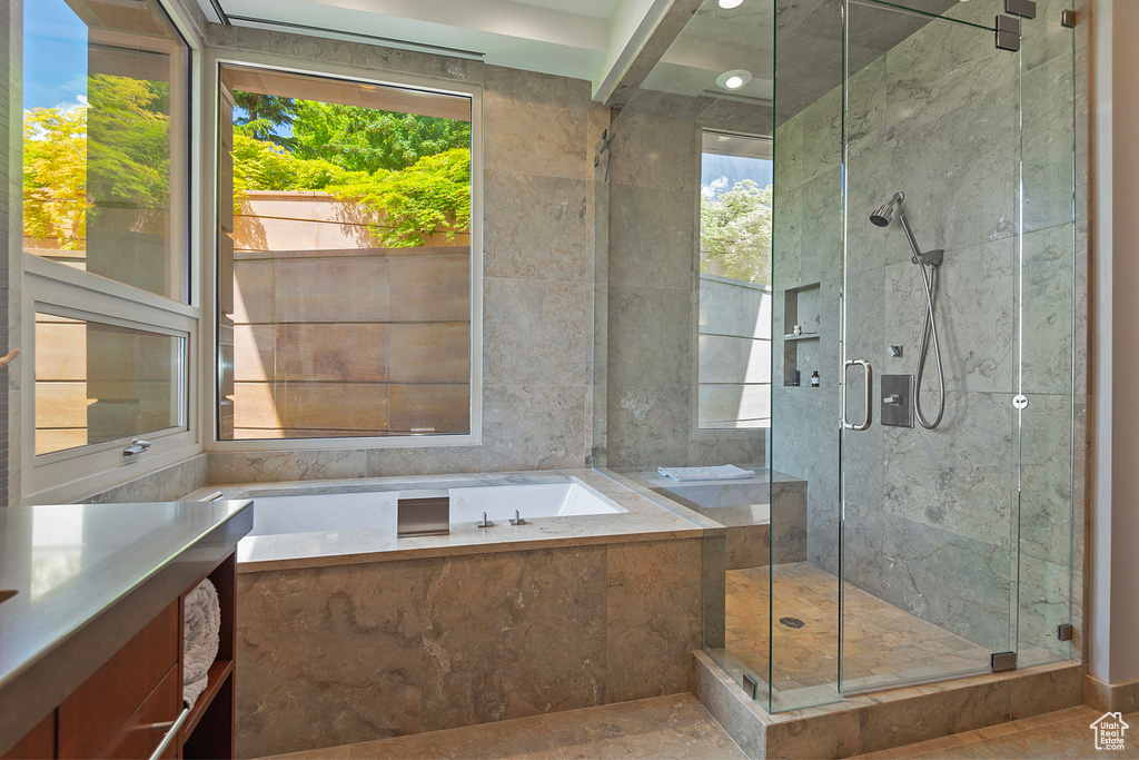 Bathroom featuring shower with separate bathtub and tile floors