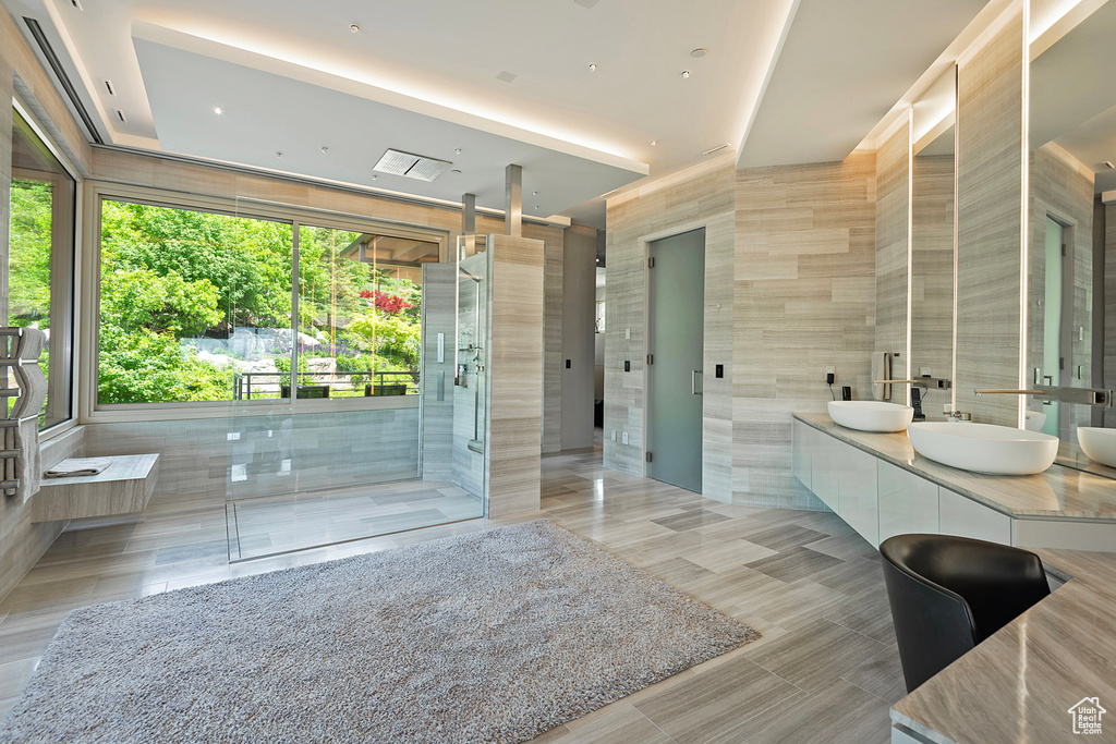 Bathroom with tile walls, double vanity, an enclosed shower, and tile flooring