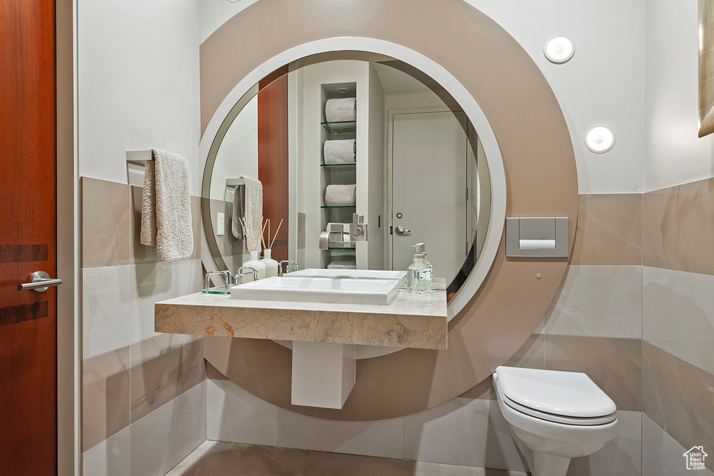 Bathroom featuring tile walls and toilet