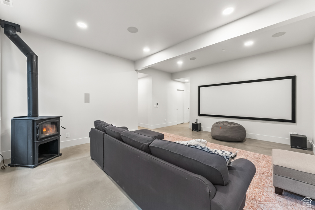 Home theater room with concrete flooring and a wood stove