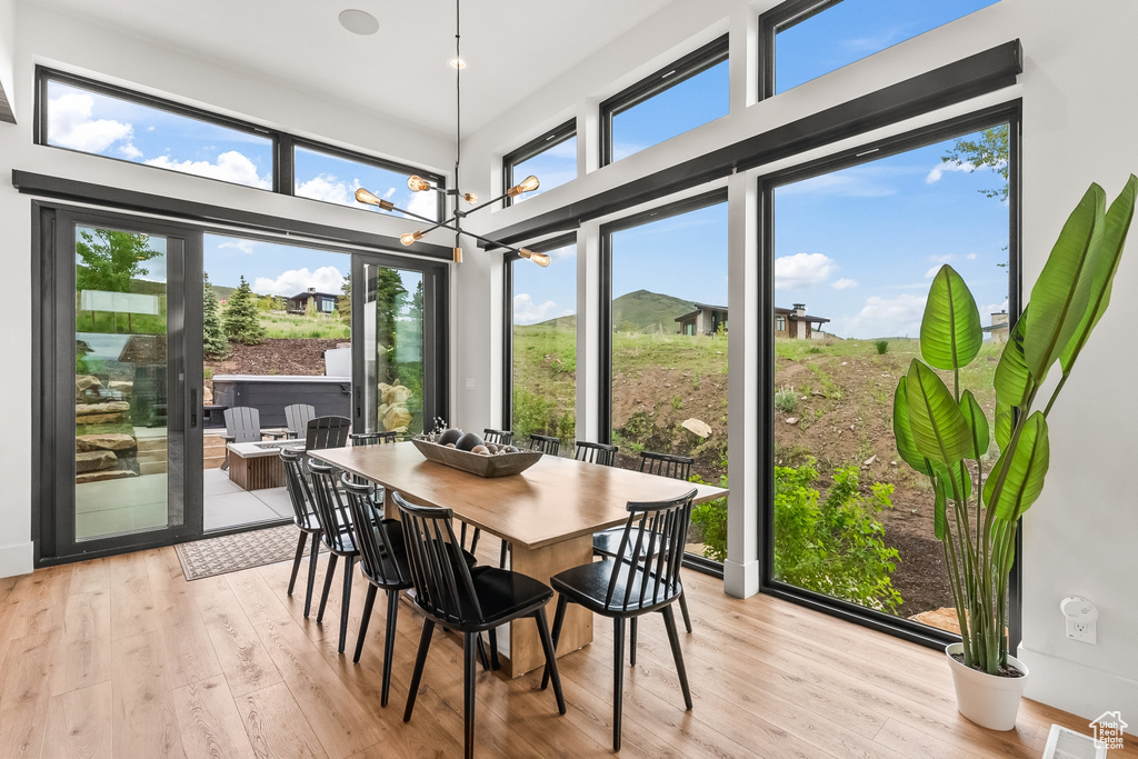 Dining space featuring a high ceiling, an inviting chandelier, and light wood-type flooring