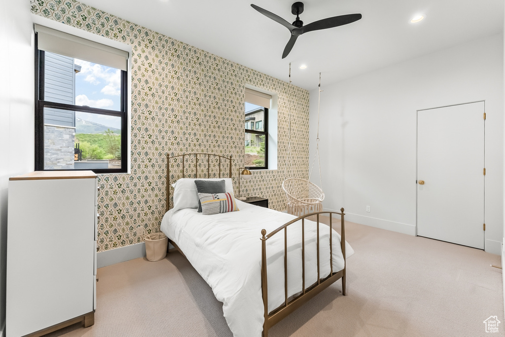 Bedroom featuring light carpet, multiple windows, and ceiling fan