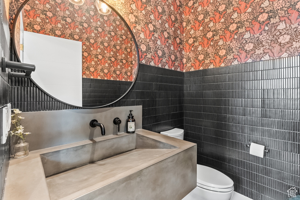 Bathroom featuring vanity, toilet, and tile walls