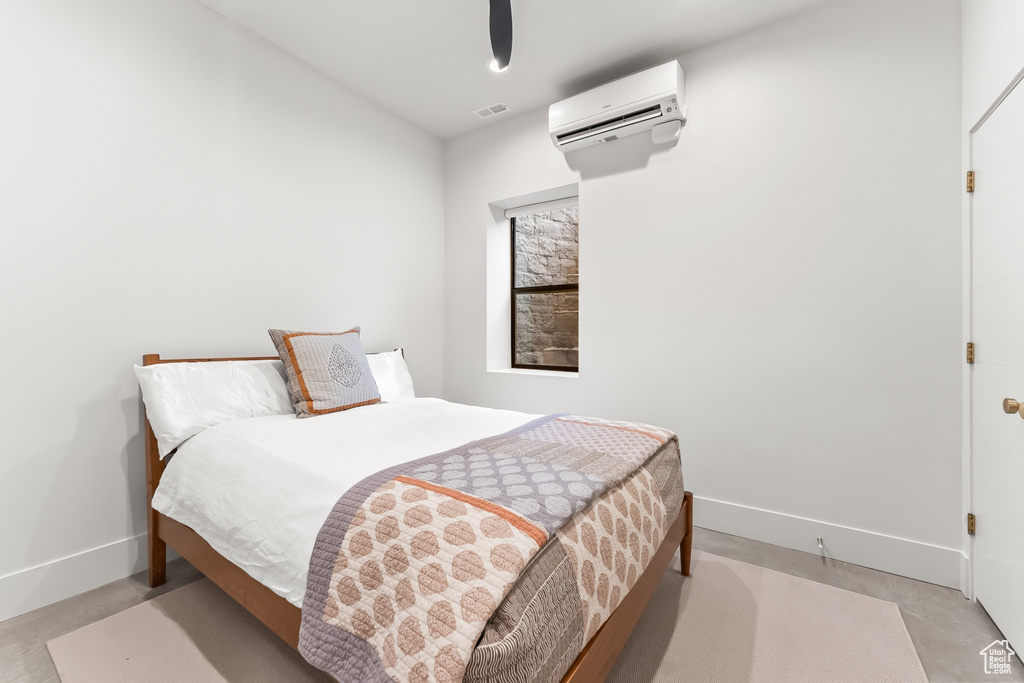 Bedroom with concrete floors and an AC wall unit