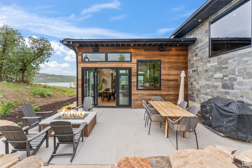 View of terrace with a fire pit, a water view, and grilling area