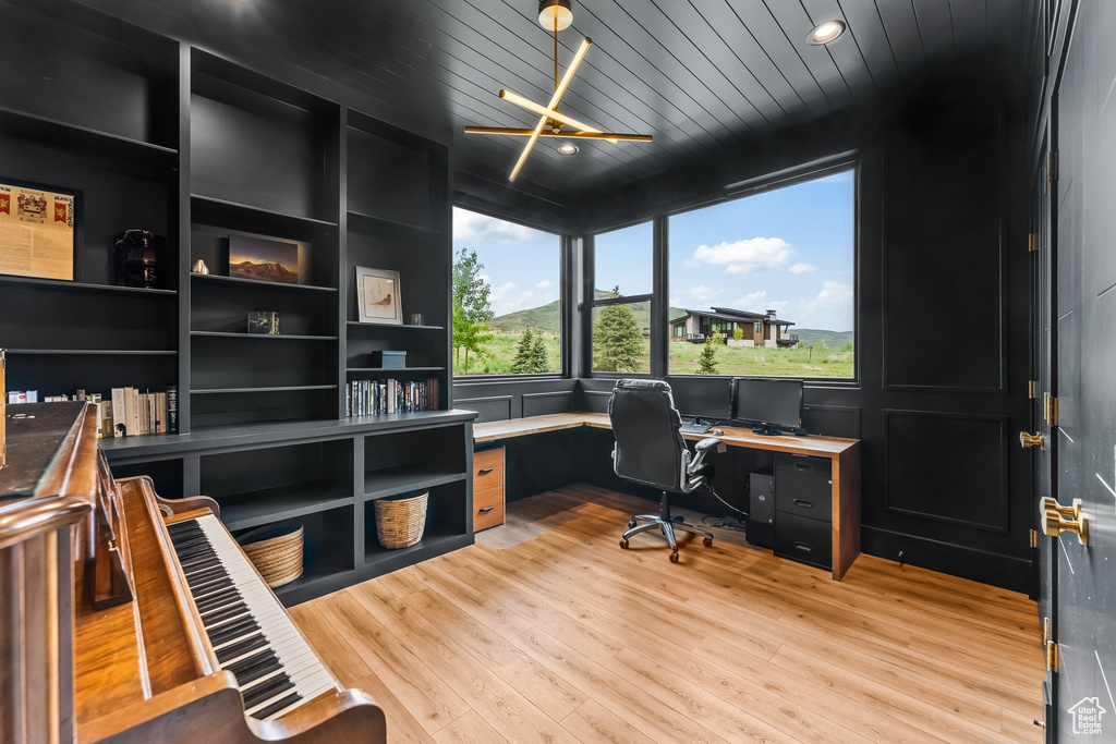 Office with built in desk and light hardwood / wood-style floors