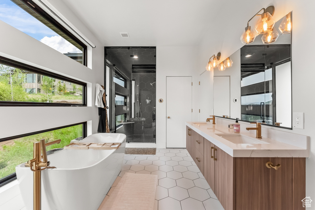 Bathroom featuring tile floors, separate shower and tub, and double sink vanity