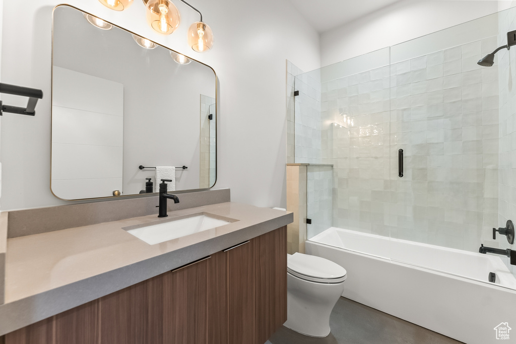 Full bathroom with enclosed tub / shower combo, vanity, and toilet