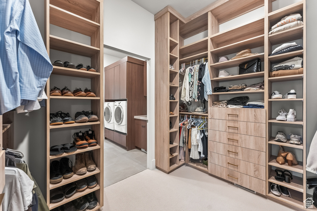 Walk in closet featuring washing machine and dryer and light colored carpet