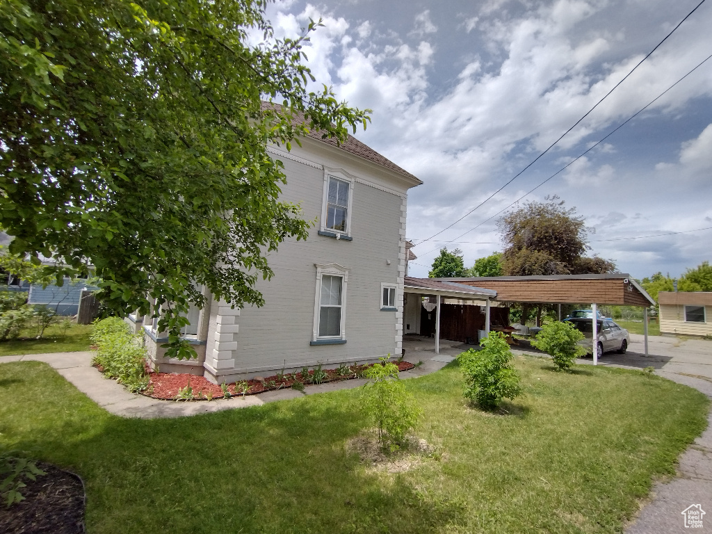Exterior space featuring a carport and a lawn