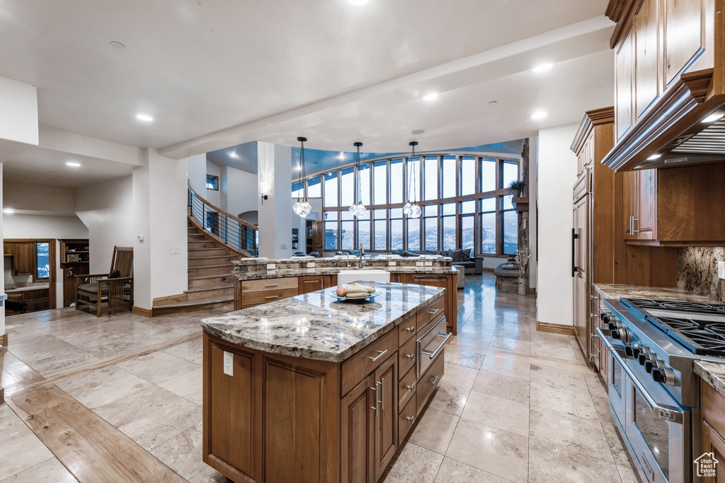 Kitchen featuring a center island, decorative light fixtures, light stone countertops, and light tile floors