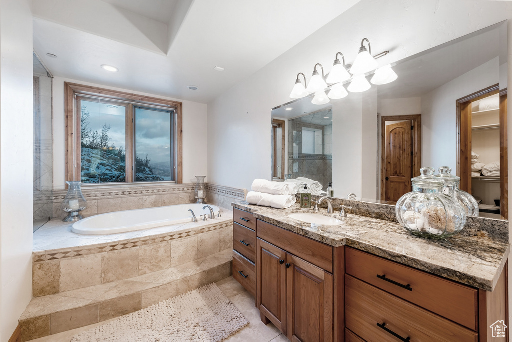 Bathroom with vanity with extensive cabinet space, tiled tub, and tile floors