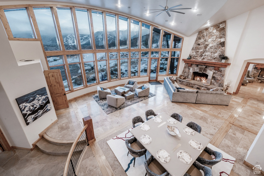 Living room with high vaulted ceiling, a stone fireplace, ceiling fan, and tile floors