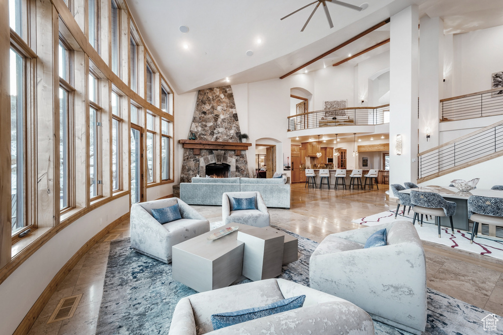 Tiled living room with high vaulted ceiling, ceiling fan, and a fireplace