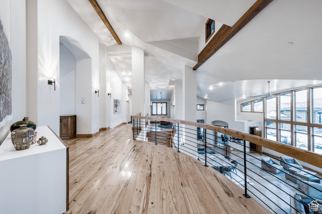 Hallway featuring beamed ceiling, high vaulted ceiling, and light wood-type flooring