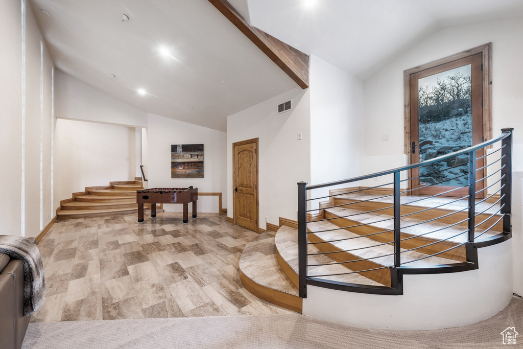 Interior space featuring lofted ceiling with beams and light wood-type flooring