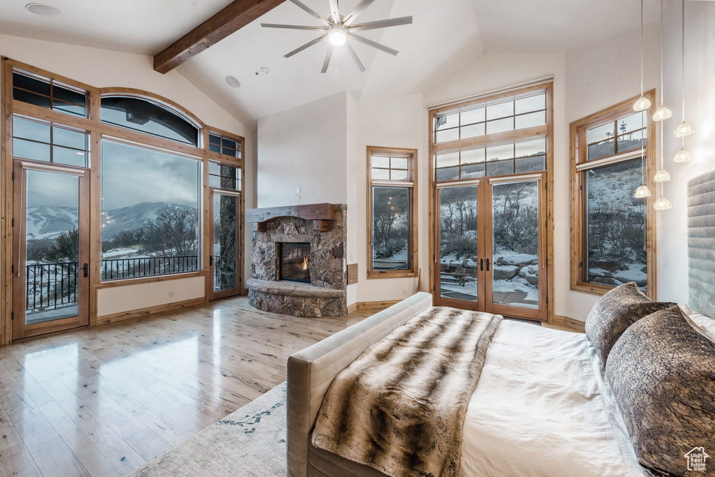 Bedroom with high vaulted ceiling, hardwood / wood-style floors, a fireplace, and multiple windows