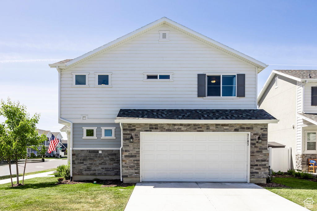 View of front of house featuring a garage and a front yard